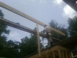 Carpenter setting a ridge beam over a new addition frame — Ice Dam Removal by Roofing Brothers in Avery Island