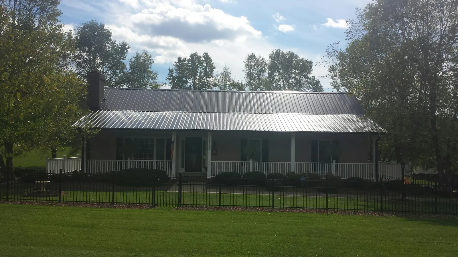 Gray metal roof on a brick ranch with a full width front porch — Gutter Guard Installation work by our crew in Avery Island