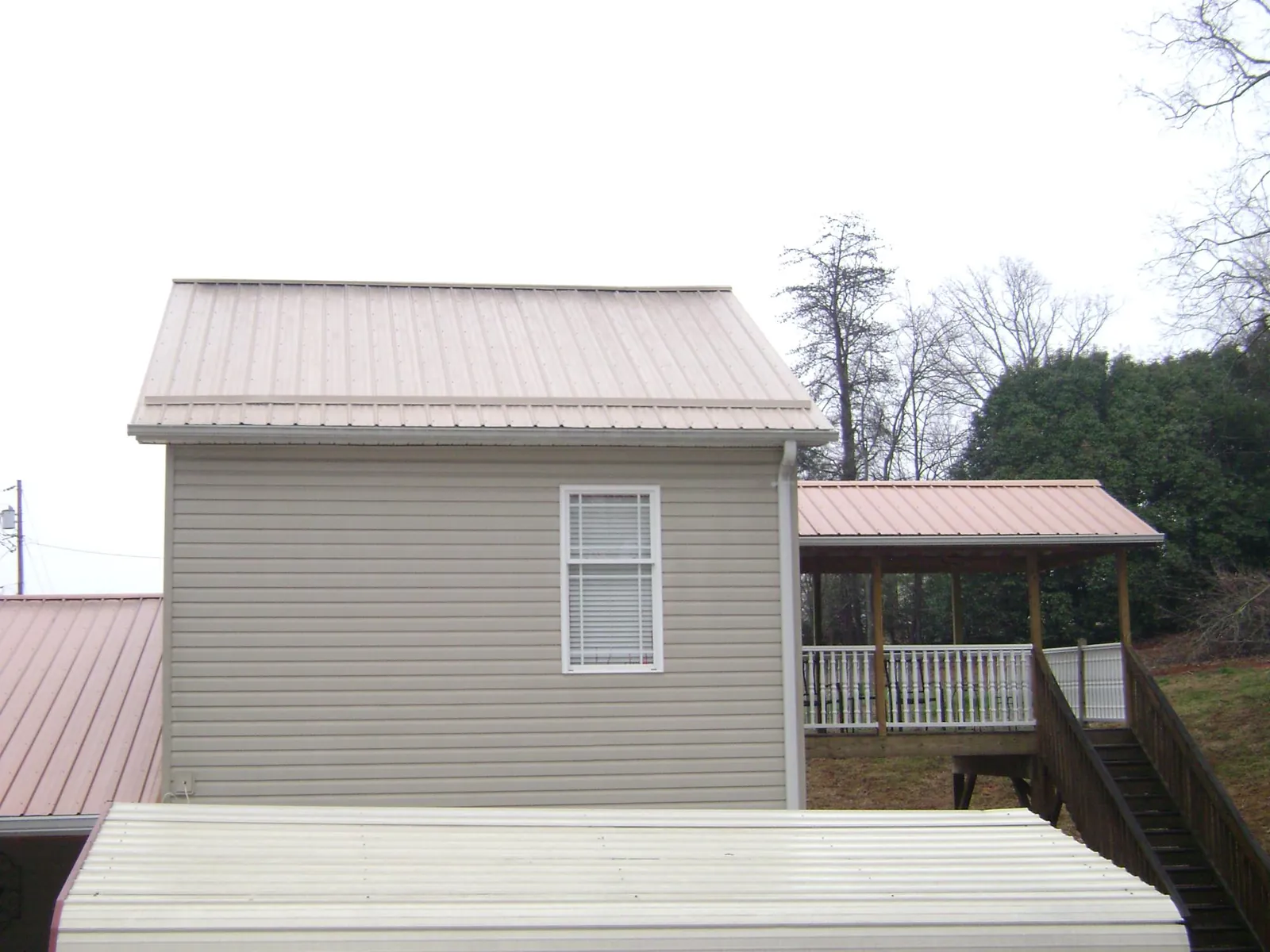 Tan metal roofs on a two story addition and attached porch, from a Roof Replacement job in Avery Island