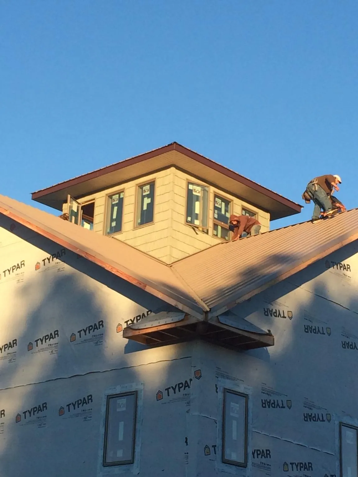 Roofers working around a rooftop cupola on a new metal roof at sunset — Roof Waterproofing in Avery Island by Roofing Brothers